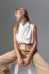 Top blanco sin mangas con cuello drapeado.