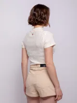 Short de tiro alto a rayas verticales en tonos beige y blanco, con cuatro bolsillos, cierre y botón metálico.