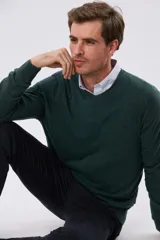 Buzo tejido de algodón color gris melange, de diseño clásico con escote en V, mangas largas y puños y ruedo acanalados. Cuenta con un pequeño bordado en el pecho.