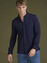 Camisa de hombre color azul marino, de piqué con cuello abotonado y manga larga.