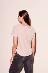 Remera color crudo de algodón peinado, de corte recto y mangas cortas. Presenta cuello redondo con detalle de cadena metálica dorada.