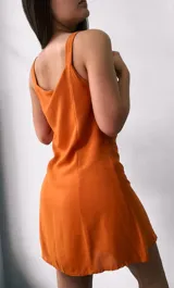 Vestido corto color mostaza con breteles finos y botones frontales. Corte acampanado.