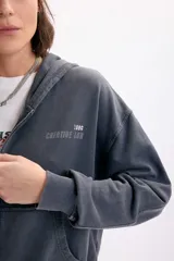 Campera deportiva con capucha y cierre frontal, de color gris con efecto acid wash. Presenta bolsillos tipo canguro, estampa con la inscripción 'Creative Lab' y detalles de pequeñas estrellas en el pecho.