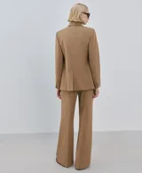 Pantalón de vestir tostado de tiro medio, con pernera ancha y recta, bolsillos laterales y pliegue planchado central.