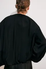 Cazadora bomber de tejido fluido en color verde, con cuello redondo, manga larga abullonada, bolsillos delanteros y cierre frontal con cremallera.