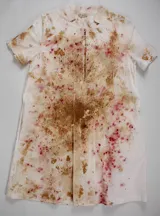 Vestido línea A de algodón cambray, teñido a mano con técnica botánica, resultando en un estampado único con manchas y salpicaduras en tonos rosados, amarillos suaves y terrosos. Presenta manga corta, bolsillos laterales, cuello limpio y una tabla frontal que añade estructura.