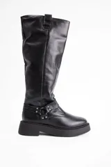 Bota de caña alta confeccionada en cuero vacuno color negro, con suela track de plataforma y detalle de tira con argolla metálica y tachas en el tobillo.