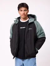Campera Rusty con capucha, diseño bicolor en negro y verde militar. Presenta cierre frontal, puños elásticos y logo de la marca bordado en el pecho.