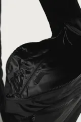 Bolso de hombro negro de nylon, con compartimento principal y bolsillos con cierre de cremallera, bolsillos laterales con cordón ajustable y asa fruncida.