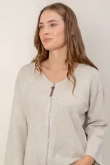 Campera de punto gris con cierre frontal completo, cuello redondo y mangas anchas. Presenta un detalle de tirador de cuero en el cierre.