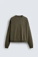 Sudadera de corte boxy fit con efecto lavado, cuello redondo con detalle de costura triangular y acabados con bordes deshilachados en el ruedo y las costuras. Presenta manga larga con puños acanalados.