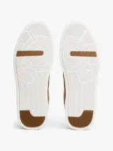 Zapatillas de corte bajo Tommy Hilfiger con diseño inspirado en el tenis, confeccionadas en piel napa blanca con paneles laterales de gamuza en color marrón. Presentan cierre con cordones, suela de goma y detalles de logo en bajo relieve.