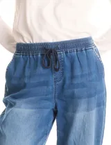 Pantalón tipo jogger de denim azul con efecto lavado. Presenta cintura elástica con cordón ajustable, bolsillos laterales y traseros, y puños elásticos en los tobillos.