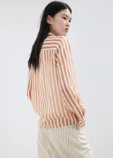 Camisa de lyocell semitransparente con estampado de rayas en tonos marrones y blancos, cuello camisero, manga larga y cierre frontal con botones.