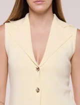 Chaleco de punto fino amarillo con escote en V, solapa tipo blazer, sin mangas y cierre frontal con dos botones dorados.