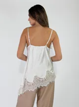Top de viscosa color lila con efecto acid wash, tirantes finos y detalles de encaje floral en el escote y en el ruedo asimétrico.