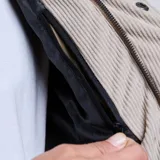 Campera parka acolchada de hombre, color beige, con cierre frontal de botones, cuello de cotelé en contraste y bolsillo en el pecho con solapa.