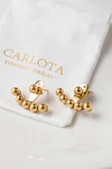 Par de aros dorados con forma curva y cinco bolitas de acero quirúrgico en cada aro.