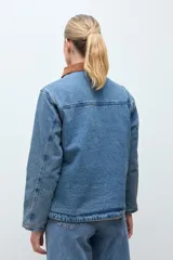 Campera de jean en tono azul medio, con cuello de pana en color marrón, cierre frontal con botones metálicos y bolsillos frontales tipo cargo.