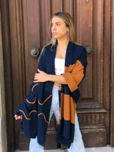 Pashmina de tejido de punto color azul marino con bloques de color camel y diseño arabesco en color naranja.