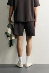Bermuda estilo jogger de ajuste relajado, confeccionada en tejido interlock de algodón. Cuenta con cintura elástica ajustable con cordón, bolsillos frontales de vivo y diseño liso.