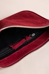 Cartera tipo bandolera de gamuza color negro, con cierre superior, tiras colgantes decorativas y herrajes metálicos plateados. Incluye asa corta para llevar al hombro y correa larga ajustable y desmontable.