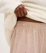 Conjunto de pijama compuesto por un buzo de cuello alto con cierre frontal parcial, confeccionado en tejido sherpa color crema con bordado de Mickey Mouse en el pecho, y un pantalón largo de satén color beige con estampado de corazones pequeños y cintura elástica.