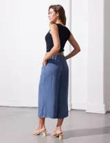 Pantalón capri de gasa bambula color beige, marca Dictionary. Tiene pretina ancha con elástico en la parte trasera, bolsillos delanteros y corte de pierna ancha. Incluye cinturón de rafia con hebilla redonda.