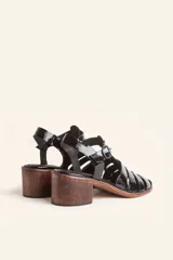 Sandalia plateada de cuero con tiras entrecruzadas, taco de madera y hebilla lateral.