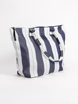 Bolso tipo tote grande, resistente al agua, con diseño de rayas verticales rojas y blancas. Cuenta con asas largas de hombro, cierre superior y parche de cuero con logo grabado. Incluye neceser transparente a juego con base y detalles a rayas.