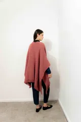 Ruana color rosa viejo de tejido de punto grueso con flecos en el borde inferior.