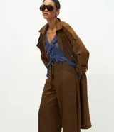 Pantalón de corte barrel con cintura estructurada, trabillas y cinto ajustable con hebilla metálica. Presenta diseño de piernas anchas con recortes laterales y bolsillos frontales.