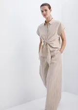 Pantalón recto color beige de tiro medio, con estampado de raya diplomática, trabillas para cinto y cierre frontal con gancho y cremallera.