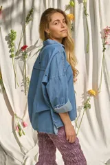 Camisa de denim suave, de corte oversize, con mangas largas abombadas, puños doblados y cierre frontal con botones nacarados.