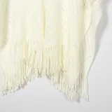 Ruana color crema con diseño calado y flecos en el borde inferior.