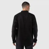 Camisa de manga larga con cuello clásico y cierre frontal de botones. Presenta un bolsillo en el pecho y puños abotonados, con un diseño de corte regular y textura natural.