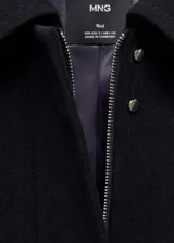 Chaqueta oversize de tejido mezcla de lana en color negro, con cuello camisero, cierre frontal de cremallera oculta, bolsillos laterales y mangas largas con puños abotonados.