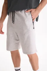 Bermuda de felpa sin friza de color negro, con cintura elastizada, cordón ajustable y bolsillos laterales con cierre. Presenta un pequeño logo estampado en el borde inferior.