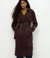 Trench coat largo de gamuza sintética con cuello peaked, cierre frontal cruzado con botones y cinturón ajustable en la cintura. Presenta mangas largas con reguladores en los puños y forro interior.