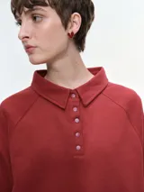 Buzo de cuello polo con escote abotonado, manga larga raglán y puños acanalados. Confeccionado en tejido suave y confortable.