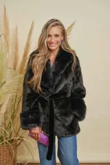 Abrigo negro de piel sintética con cuello solapa, manga larga y cinturón de tela para ajustar en la cintura.