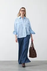 Camisa blanca de algodón con diseño utilitario y calce relajado. Presenta dos bolsillos frontales de estilo cargo con tapa y costuras a contratono.