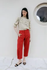 Pantalón rojo de corte recto y largo al tobillo, con bolsillos laterales y detalles de pinzas en las piernas.