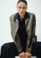 Chaqueta Sabi de cuero sintético en color verde militar, con cuello camisero, cierre frontal con botones y bolsillos de parche delanteros.