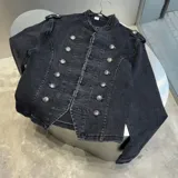 Chaqueta de denim negro con diseño de estilo militar, cuello mao, doble botonadura frontal con botones metálicos decorativos y presillas en los hombros.