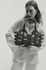 Bolso tipo tote grande de tela revestida marrón con estructura exterior trenzada imitando cuero y bolsa interior de lona de algodón y lino con cordón ajustable.