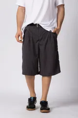 Bermuda sastrera baggy de color negro con diseño de rayas diplomáticas finas blancas. Presenta pinzas en la parte frontal y calce holgado.