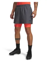 Short deportivo Under Armour de corte estándar, color gris, con cintura elástica y bolsillos laterales. Presenta un diseño de doble capa con calza interna integrada en color naranja neón.