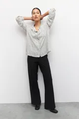 Pantalón de vestir negro de corte ancho y tiro alto, con elástico en la cintura y costuras verticales decorativas a lo largo de las piernas.