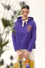 Buzo lila de corte recto, con capucha ajustable con lazo color crema y estampado frontal con letras en animal print.